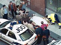 Cadaver de Abad cubierto en la acera